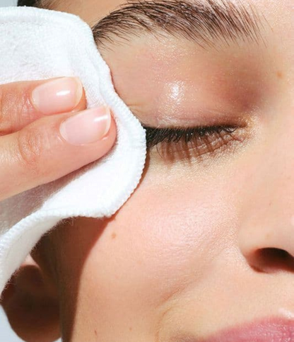 Femme se nettoyant et se démaquillant le visage avec un coton imbibé d’eau florale de rose de Damas, soin naturel apaisant et hydratant pour une peau fraîche et éclatante.